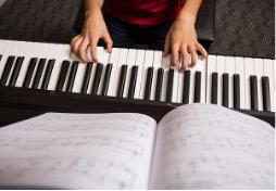 Student playing the piano and reading sheet music