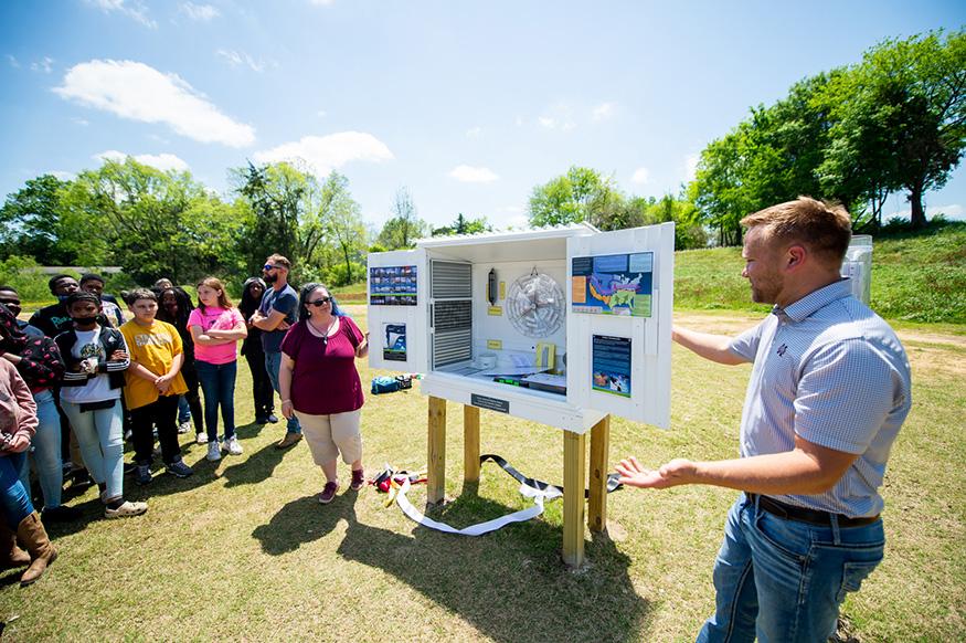 MSU Department of Geosciences Assistant Clinical Professors Sarah Lalk and Barrett Gutter show Partnership Middle School students how the new weather station installed at the school is used to collect data such as temperature, barometric pressure, precipitation, wind speed and humidity
